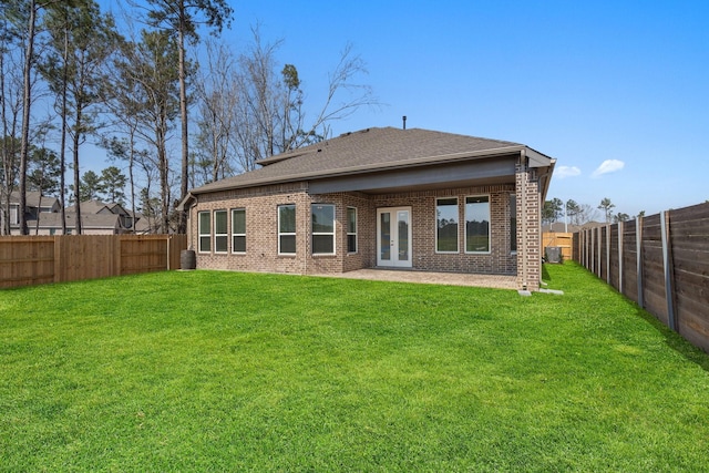 rear view of property with a patio, a fenced backyard, brick siding, a shingled roof, and a yard