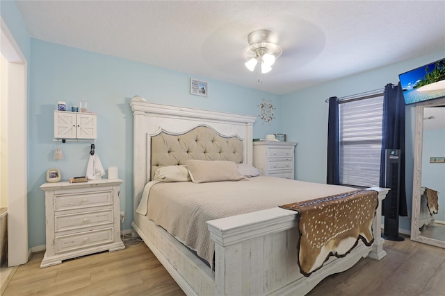 bedroom with light wood finished floors, a ceiling fan, and baseboards