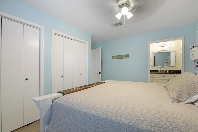 bedroom with visible vents, connected bathroom, ceiling fan, light wood-type flooring, and multiple closets