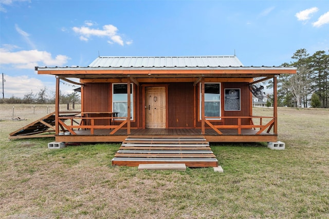 rear view of house featuring metal roof and a yard