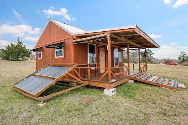 rear view of property with metal roof and a lawn