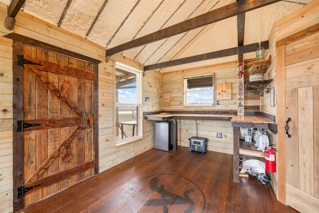 kitchen featuring freestanding refrigerator, dark wood finished floors, wooden walls, and lofted ceiling with beams