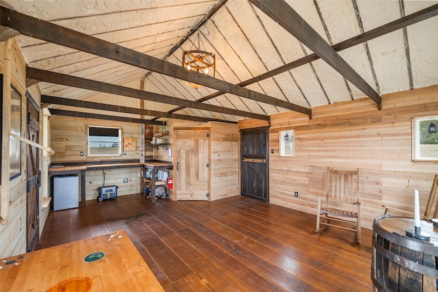 unfurnished living room with vaulted ceiling with beams, hardwood / wood-style flooring, and wooden walls