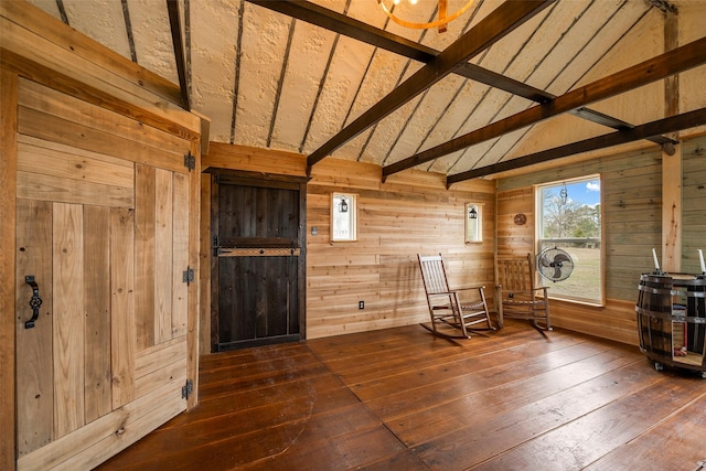 unfurnished room featuring vaulted ceiling with beams, wood-type flooring, and wooden walls