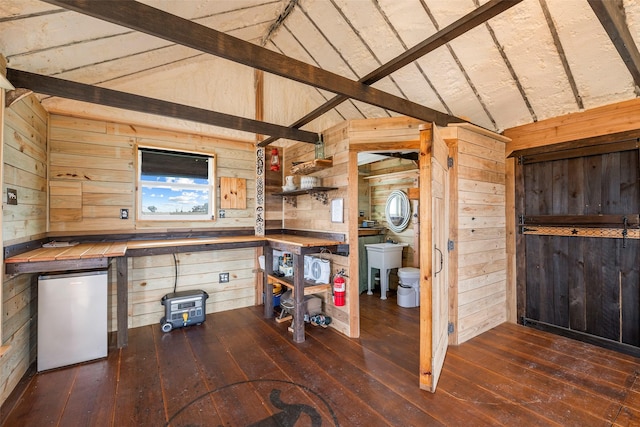 interior space featuring vaulted ceiling with beams, refrigerator, wood-type flooring, and wood walls