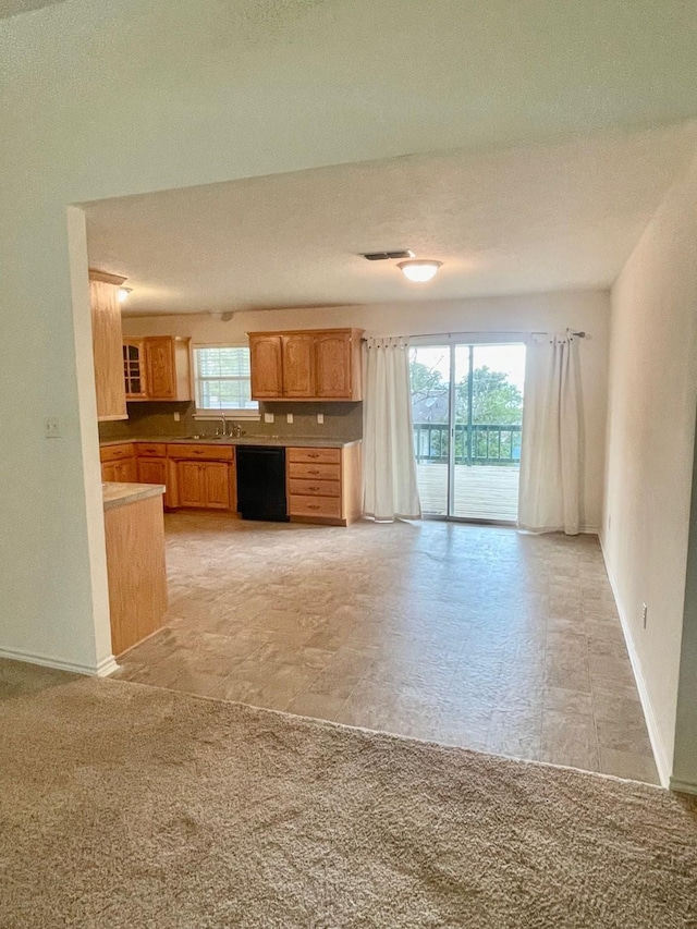 kitchen featuring light colored carpet, visible vents, a sink, dishwasher, and baseboards