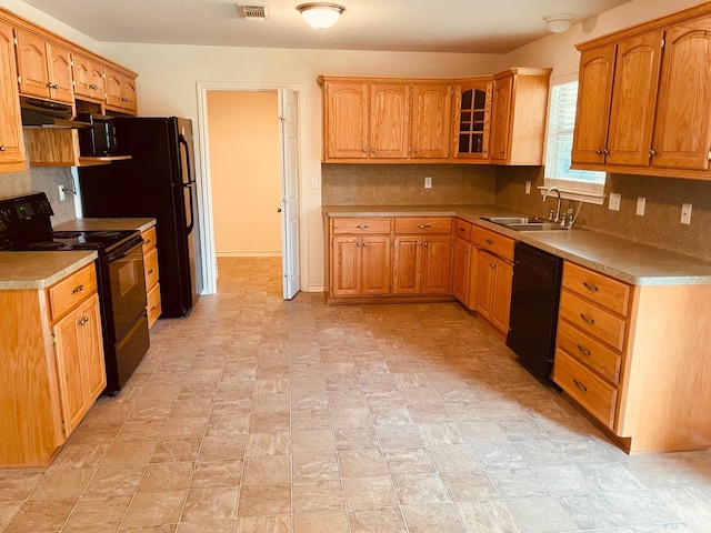 kitchen featuring black appliances, backsplash, a sink, and under cabinet range hood