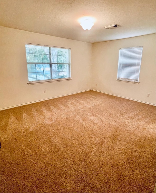 carpeted empty room featuring visible vents and a textured ceiling