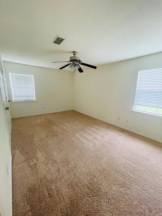 unfurnished room featuring ceiling fan, carpet floors, visible vents, and baseboards