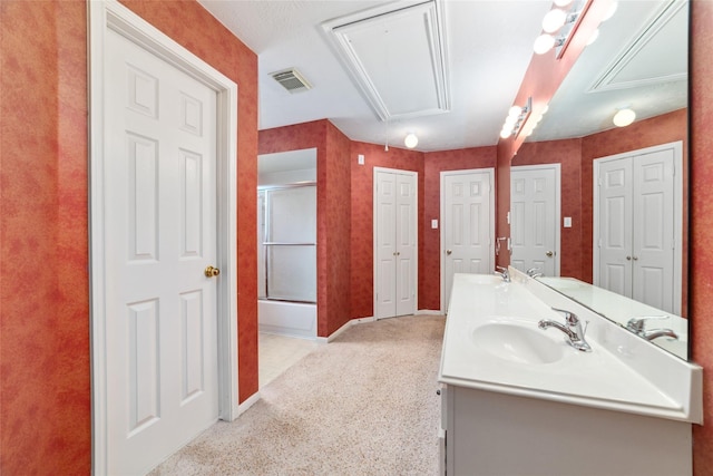 bathroom featuring double vanity, a shower with door, visible vents, and a sink