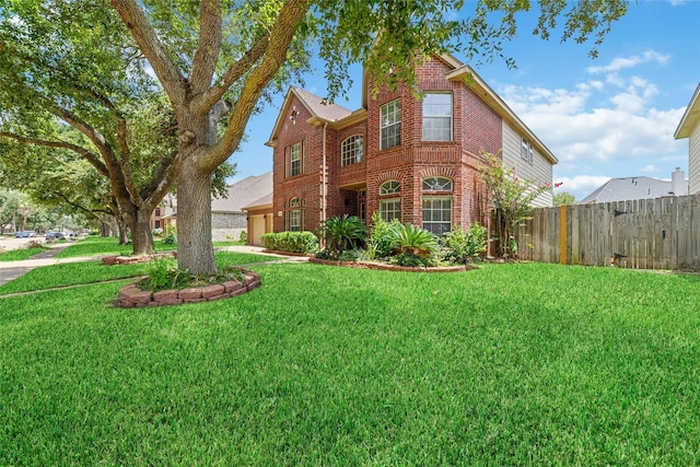 view of front facade featuring a garage, a front yard, brick siding, and fence