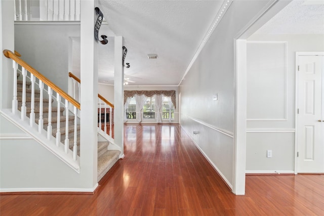 foyer featuring ornamental molding, a textured ceiling, and wood finished floors