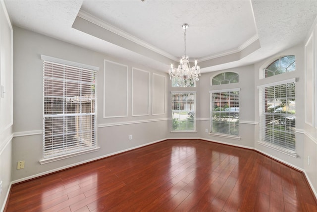 unfurnished room featuring a tray ceiling, a textured ceiling, baseboards, and wood finished floors