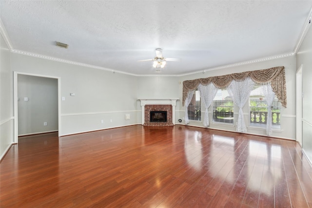 unfurnished living room with ceiling fan, a textured ceiling, a fireplace, wood finished floors, and visible vents