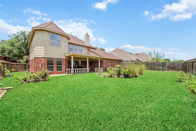 back of house featuring brick siding, a fenced backyard, a chimney, and a vegetable garden