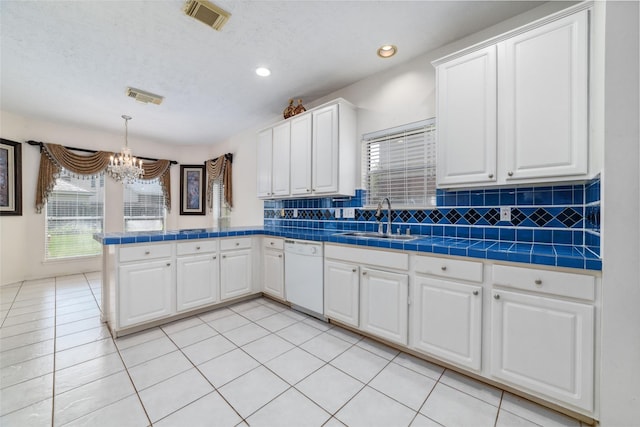 kitchen featuring visible vents, white dishwasher, a peninsula, and a sink