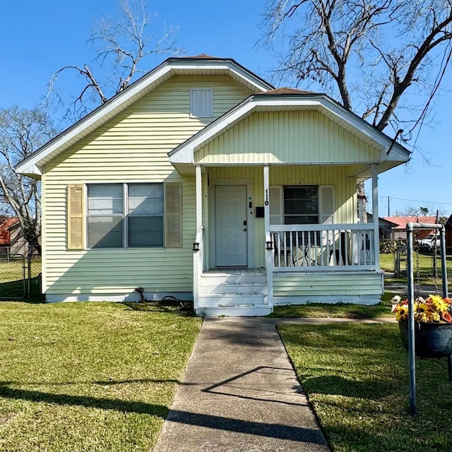 bungalow-style house with covered porch, a front lawn, and fence