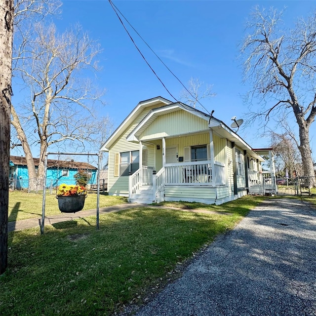 bungalow-style home featuring driveway, a porch, and a front yard