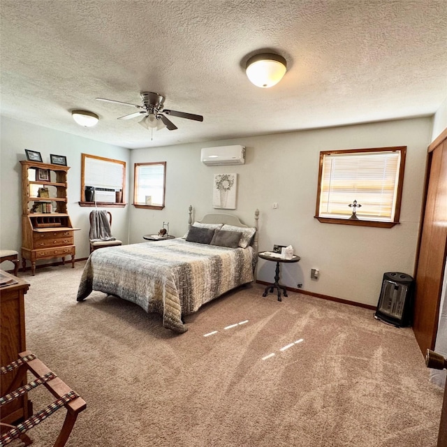 bedroom with a wall unit AC, carpet, baseboards, and a textured ceiling