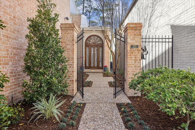 entrance to property featuring brick siding and a gate