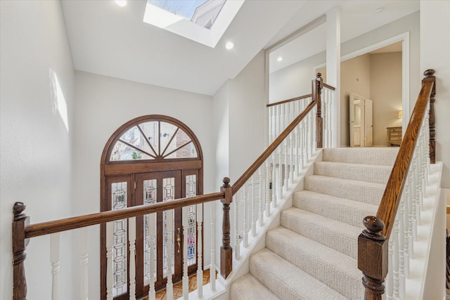 stairs featuring high vaulted ceiling, a skylight, and recessed lighting