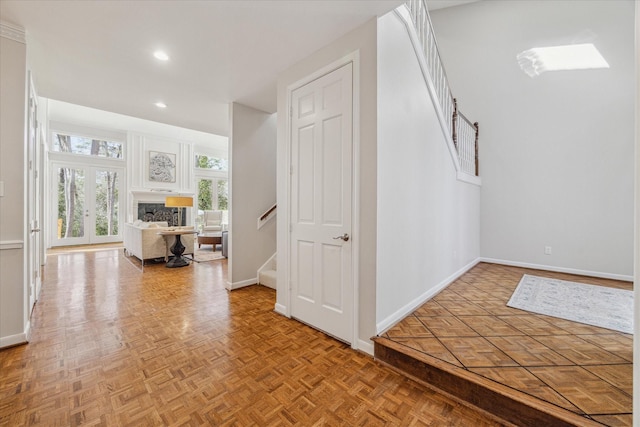 foyer entrance with french doors, a fireplace, recessed lighting, baseboards, and stairs