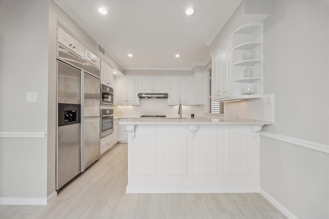 kitchen featuring built in refrigerator, a peninsula, under cabinet range hood, stainless steel oven, and open shelves