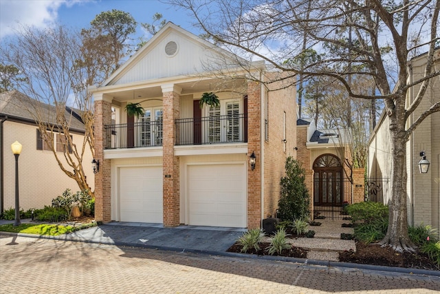 view of front facade with a balcony, an attached garage, decorative driveway, and brick siding