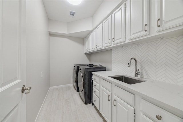 clothes washing area featuring cabinet space, visible vents, baseboards, washer and clothes dryer, and a sink