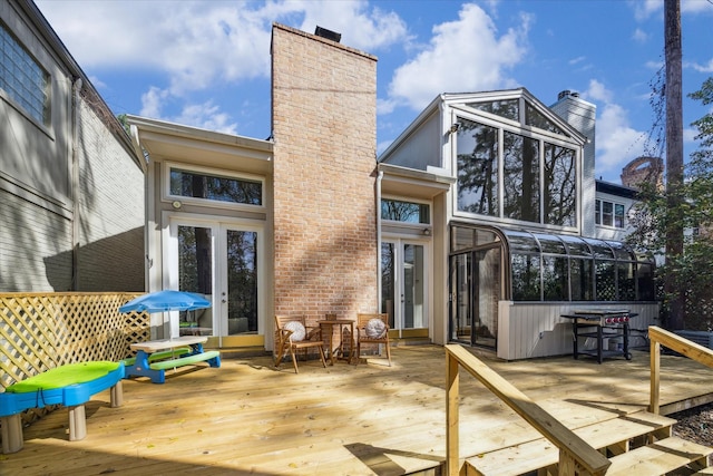 back of property with a deck, french doors, and a chimney