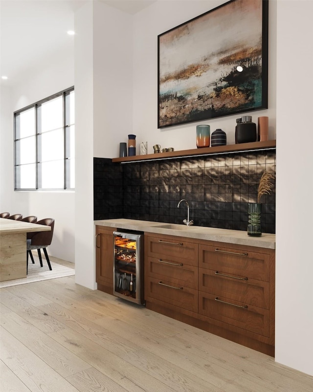 bar featuring wine cooler, indoor wet bar, a sink, and light wood-style floors