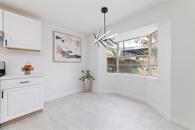 unfurnished dining area featuring a chandelier and baseboards