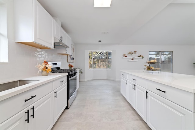 kitchen with tasteful backsplash, gas stove, white cabinets, light stone countertops, and under cabinet range hood