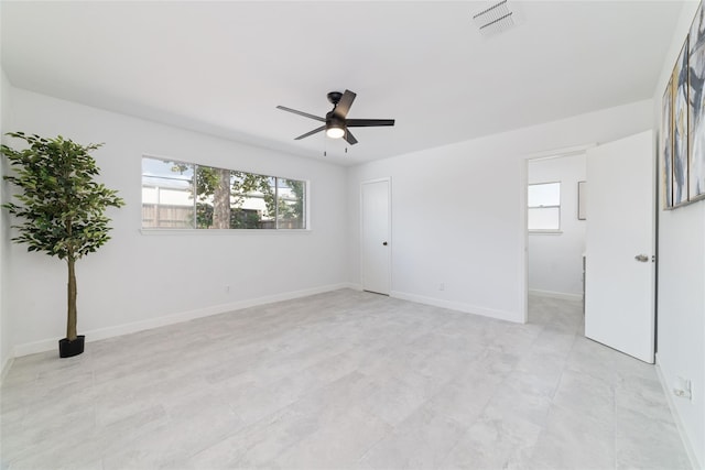 unfurnished room featuring a healthy amount of sunlight, visible vents, baseboards, and a ceiling fan