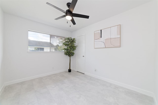 spare room with a ceiling fan and baseboards