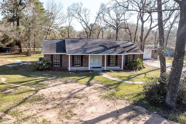 view of front facade featuring covered porch, brick siding, driveway, and a front lawn