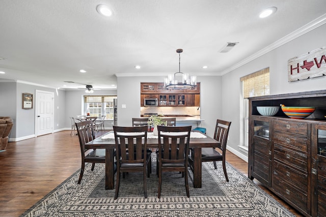 dining area with baseboards, visible vents, ornamental molding, and dark wood-type flooring