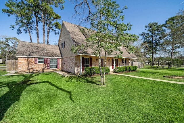 view of front of property with brick siding, a front lawn, and fence