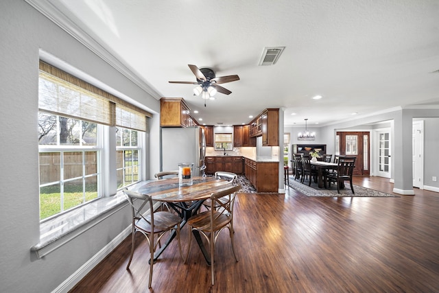 dining room featuring ornamental molding, dark wood-style flooring, visible vents, and baseboards