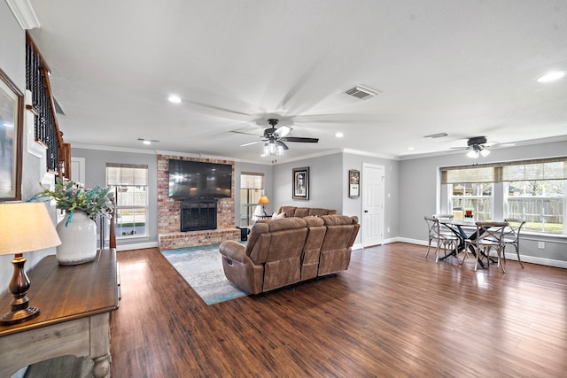 living area featuring plenty of natural light, a brick fireplace, dark wood finished floors, and visible vents