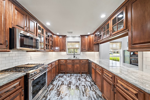 kitchen with light stone counters, stainless steel appliances, a sink, visible vents, and backsplash