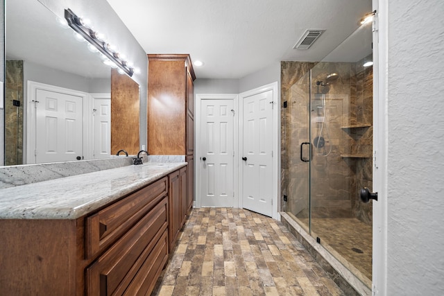 bathroom featuring vanity, a shower stall, and visible vents