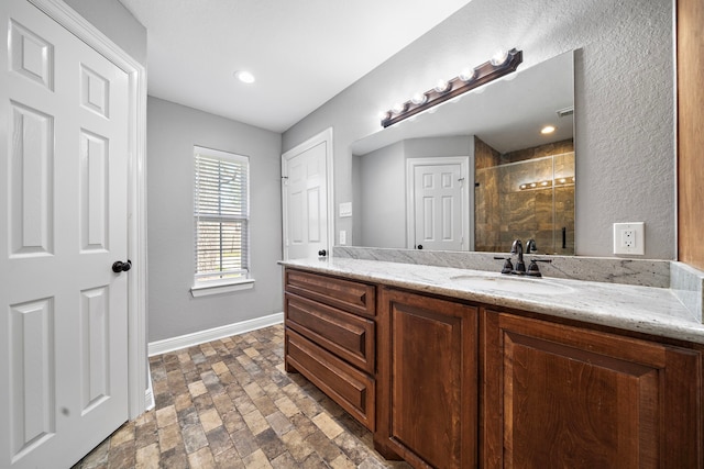 full bath with a sink, a shower stall, baseboards, and double vanity