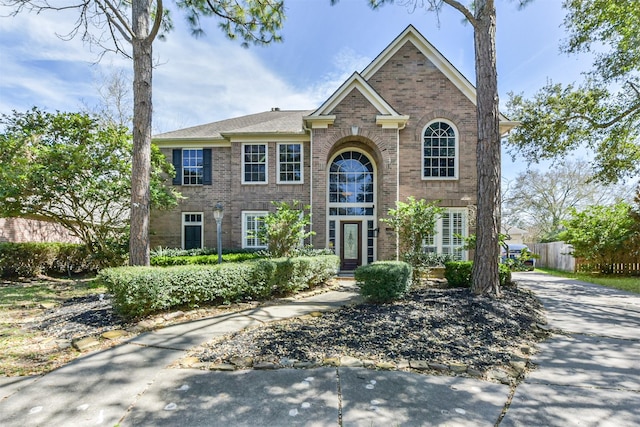 traditional-style house featuring brick siding and fence