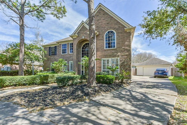 traditional home with a garage, brick siding, fence, and an outbuilding