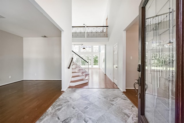 foyer featuring a towering ceiling, stairs, baseboards, and wood finished floors