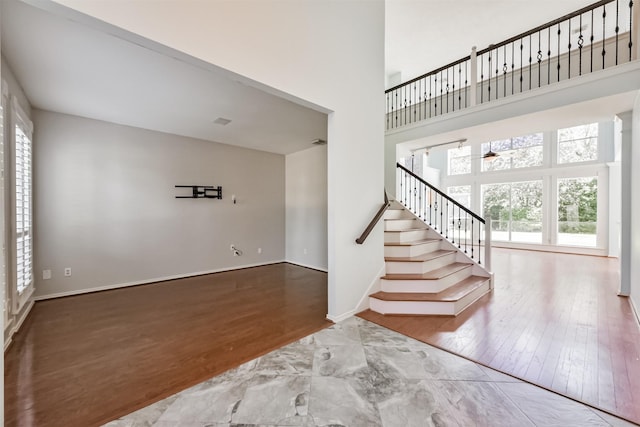 interior space with a healthy amount of sunlight, stairway, a high ceiling, and wood finished floors