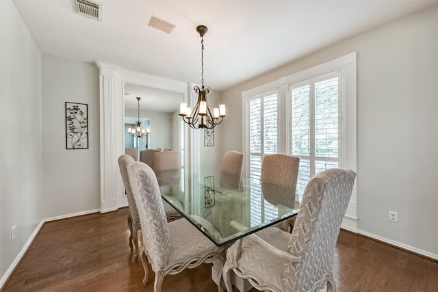 dining space with visible vents, a notable chandelier, baseboards, and wood finished floors