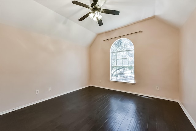 spare room featuring a ceiling fan, dark wood-style flooring, vaulted ceiling, and baseboards