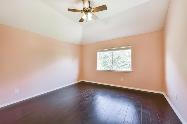 spare room featuring vaulted ceiling, dark wood finished floors, a ceiling fan, and baseboards